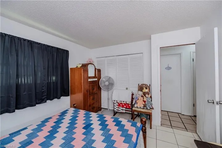 Bedroom featuring a textured ceiling, light tile patterned floors, and a closet