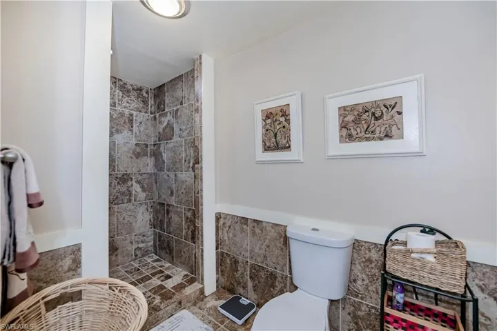 Bathroom with toilet, tile walls, and tiled shower