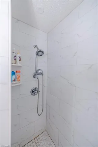 Bathroom with a textured ceiling and a tile shower