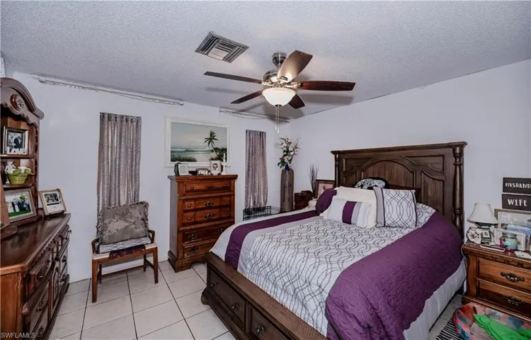 Tiled bedroom with ceiling fan and a textured ceiling