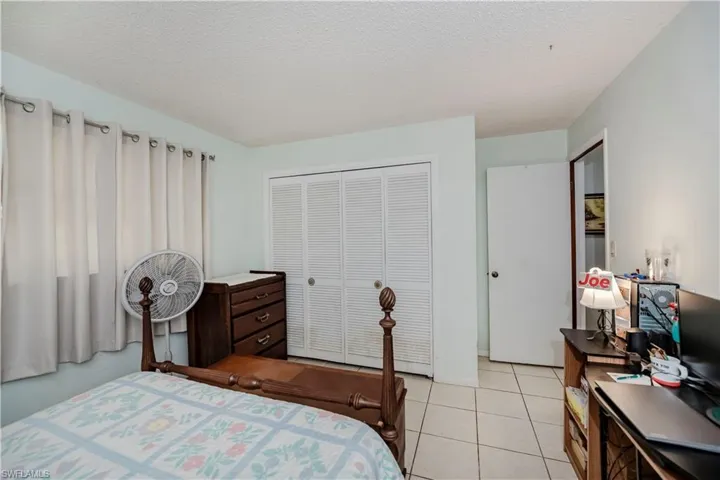 Tiled bedroom featuring a textured ceiling and a closet