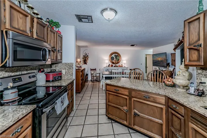 Kitchen with a textured ceiling, light tile patterned floors, stainless steel appliances, and tasteful backsplash