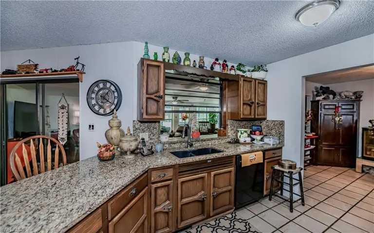 Kitchen featuring light tile patterned floors, sink, black dishwasher, and a textured ceiling