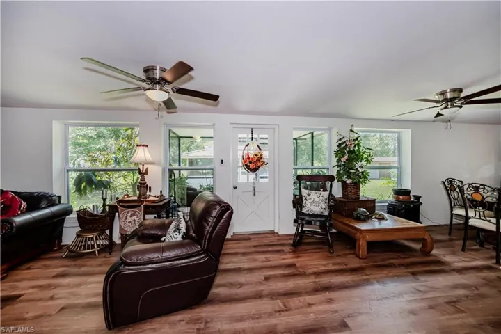Living room with ceiling fan, dark wood-type flooring, and a wealth of natural light