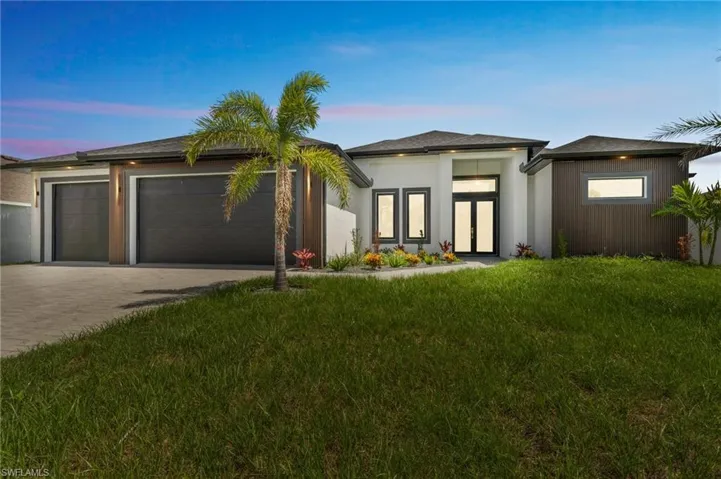 Prairie-style house featuring a front lawn, decorative driveway, an attached garage, french doors, and stucco siding