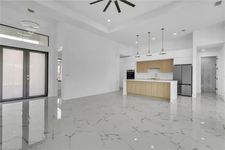 Unfurnished living room featuring a towering ceiling, light marble finish floors, french doors, and recessed lighting
