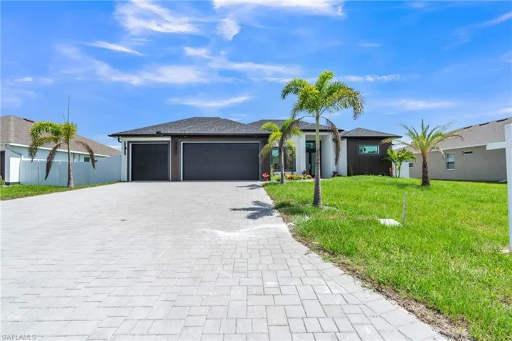 View of front of house with a front lawn, decorative driveway, and an attached garage