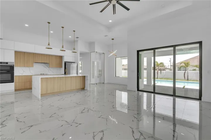 Kitchen featuring modern cabinets, decorative light fixtures, a high ceiling, a raised ceiling, and a chandelier