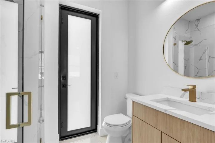 Full bath with a marble finish shower, light marble finish floors, and vanity