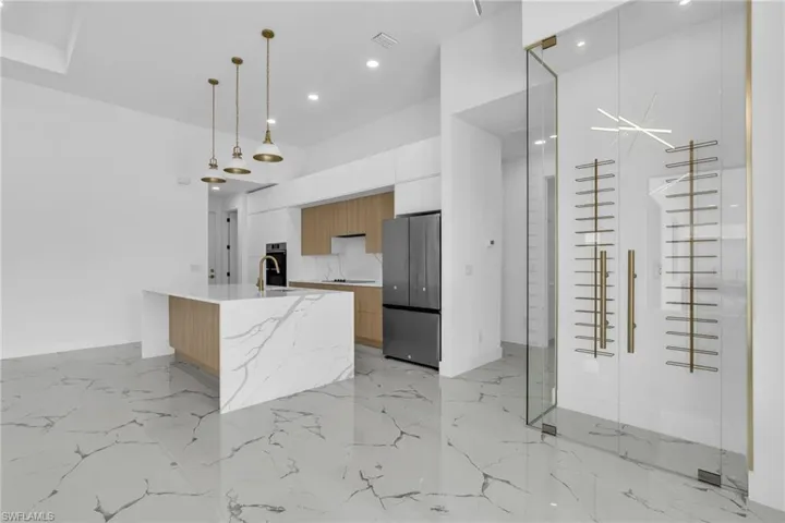 Kitchen featuring modern cabinets, light marble finish flooring, freestanding refrigerator, pendant lighting, and recessed lighting