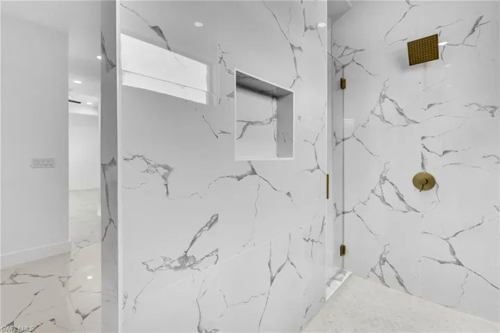 Bathroom with a marble finish shower and recessed lighting