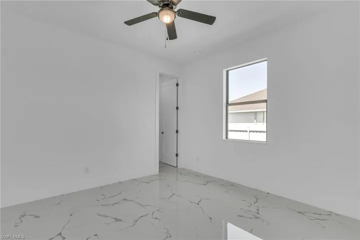 Spare room with light marble finish floors and a ceiling fan