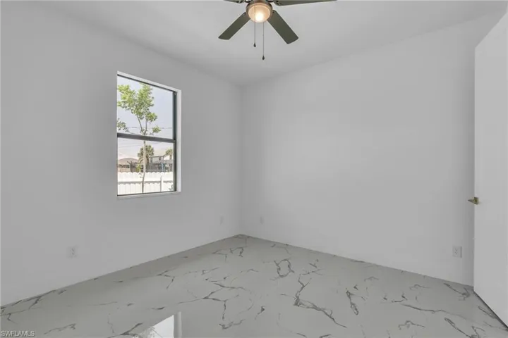Unfurnished room featuring light marble finish flooring and ceiling fan
