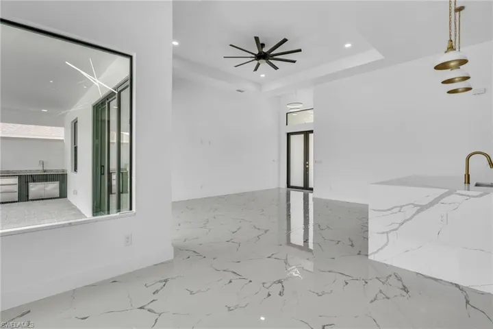Unfurnished living room featuring recessed lighting, light marble finish flooring, and a tray ceiling
