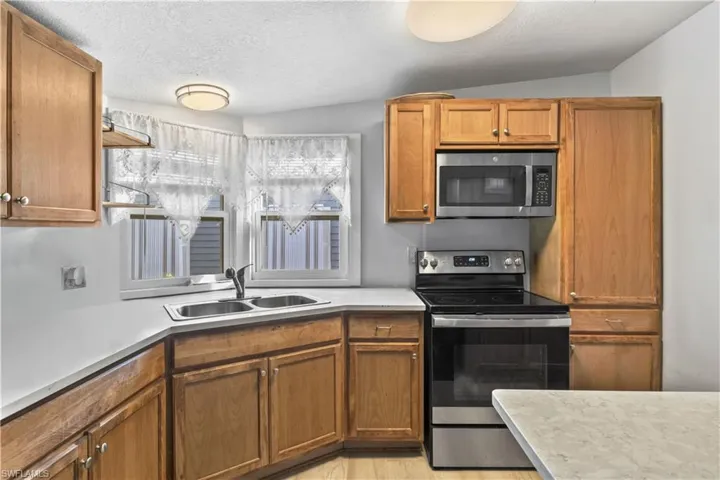 The kitchen offers cabinetry, stainless steel appliances, counter space, and breakfast bar seating