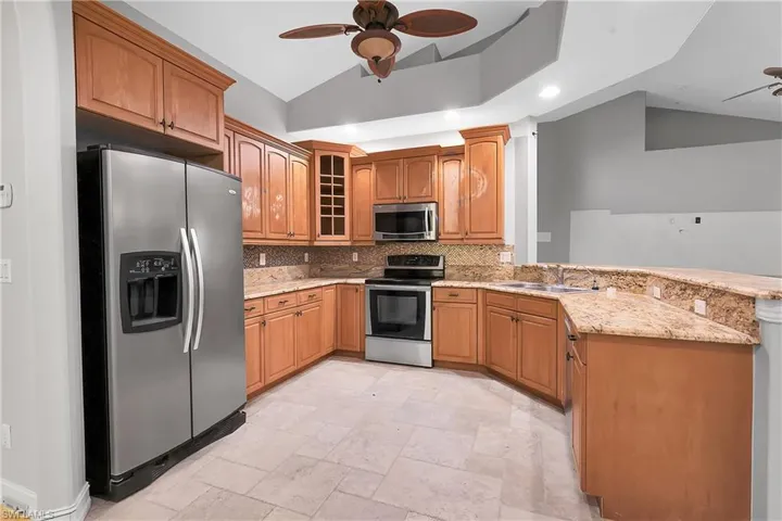 Kitchen with sink, backsplash, kitchen peninsula, vaulted ceiling, and appliances with stainless steel finishes