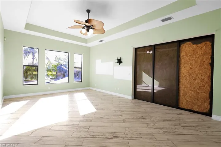 Unfurnished room with a raised ceiling, ceiling fan, and light wood-type flooring