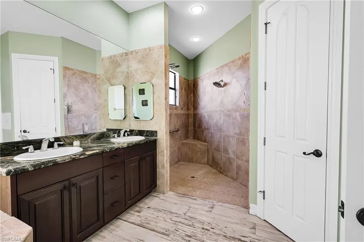 Bathroom featuring a tile shower, hardwood / wood-style floors, and vanity