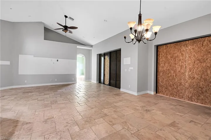 Spare room featuring ceiling fan with notable chandelier and high vaulted ceiling