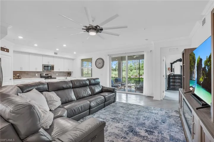 Living room featuring crown molding, sink, light tile patterned floors, and ceiling fan