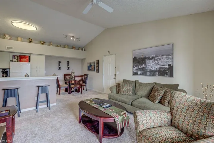 Carpeted living room featuring lofted ceiling, a textured ceiling, and a ceiling fan
