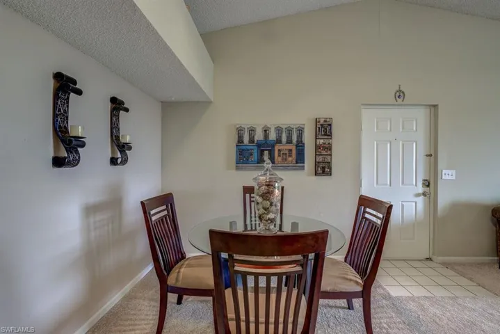 Dining area with carpet, lofted ceiling, tile patterned floors, and a textured ceiling