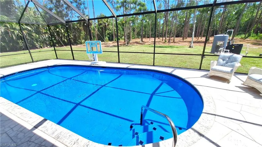 Outdoor pool with glass enclosure, a patio, and a yard