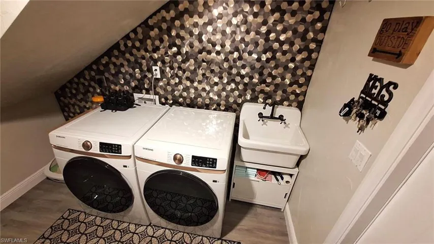 Laundry area with baseboards, laundry area, washing machine and dryer, and wood finished floors