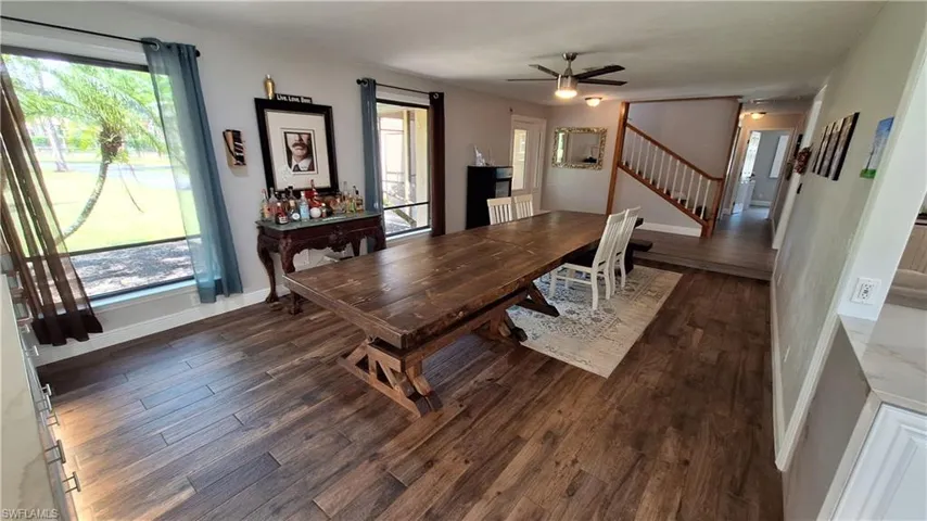 Dining area with dark wood-style flooring, stairway, and a ceiling fan