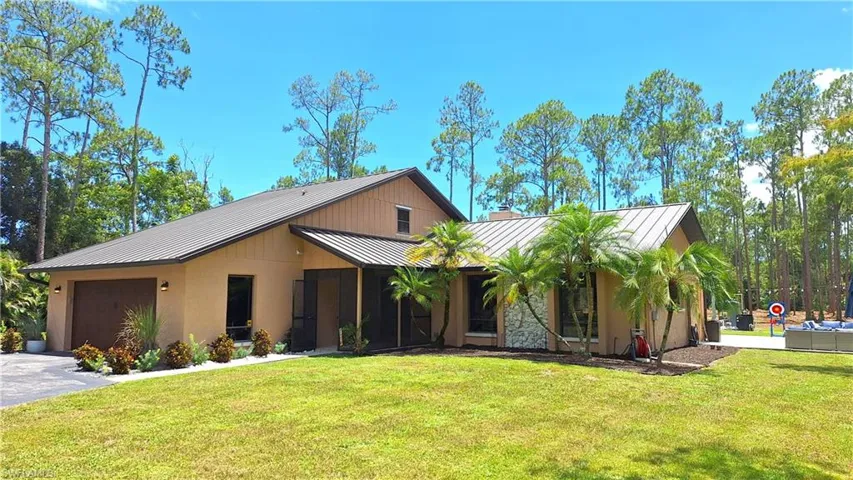 View of front facade with a garage, a standing seam roof, a metal roof, and a front lawn