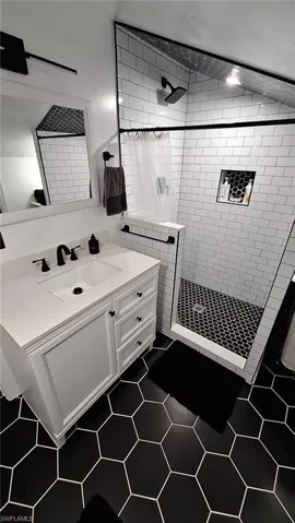 Bathroom featuring a tile shower, tile patterned flooring, and vanity