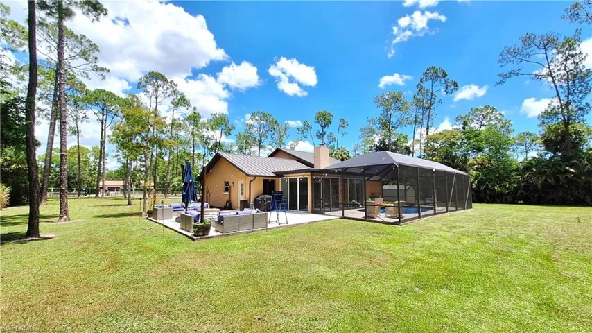 Back of house with a patio area, outdoor lounge area, a lanai, a yard, and a metal roof