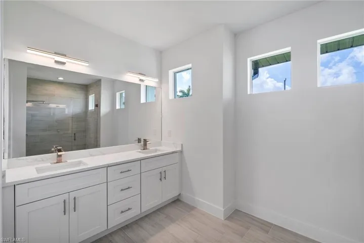 Bathroom with walk in shower, a healthy amount of sunlight, and vanity