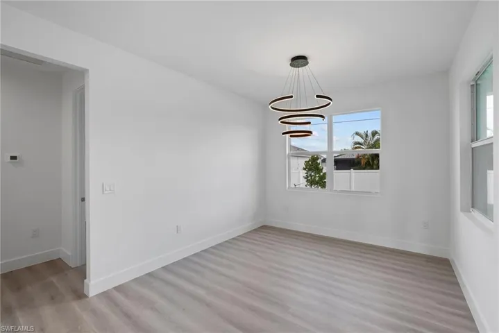 Unfurnished room with an inviting chandelier, light hardwood / wood-style flooring, and plenty of natural light
