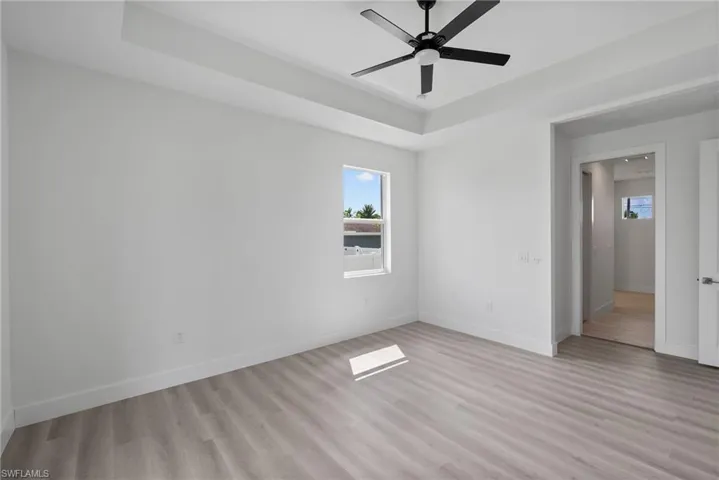 Empty room featuring a raised ceiling, ceiling fan, and light hardwood / wood-style flooring