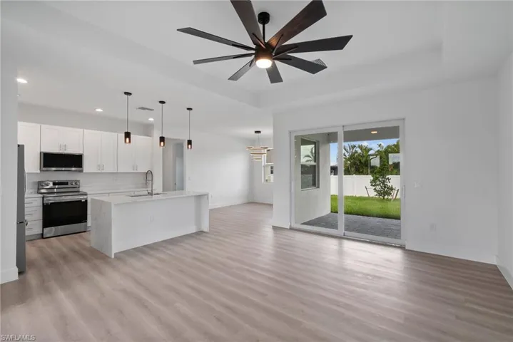 Kitchen featuring a kitchen island with sink, sink, white cabinets, appliances with stainless steel finishes, and ceiling fan