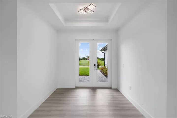 Doorway to outside with wood-type flooring, a raised ceiling, and french doors