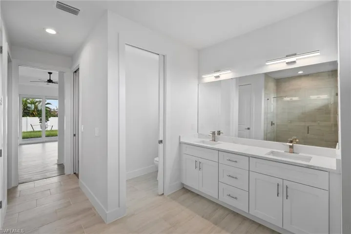 Bathroom featuring ceiling fan, vanity, hardwood / wood-style flooring, toilet, and a shower with door