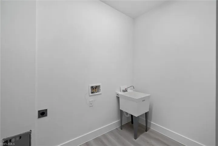 Washroom with hookup for an electric dryer, light hardwood / wood-style floors, and hookup for a washing machine