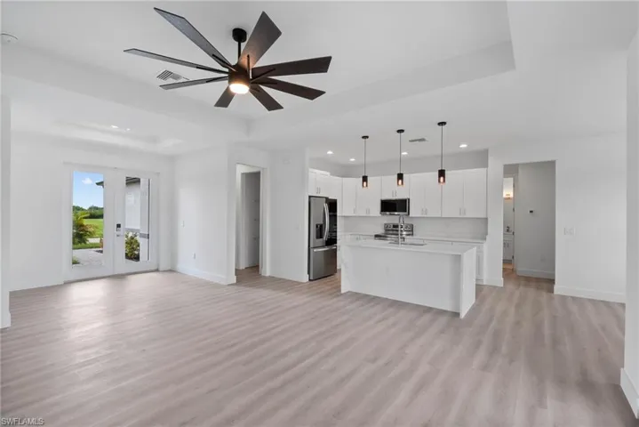 Kitchen featuring light wood-type flooring, a kitchen island with sink, white cabinetry, appliances with stainless steel finishes, and ceiling fan