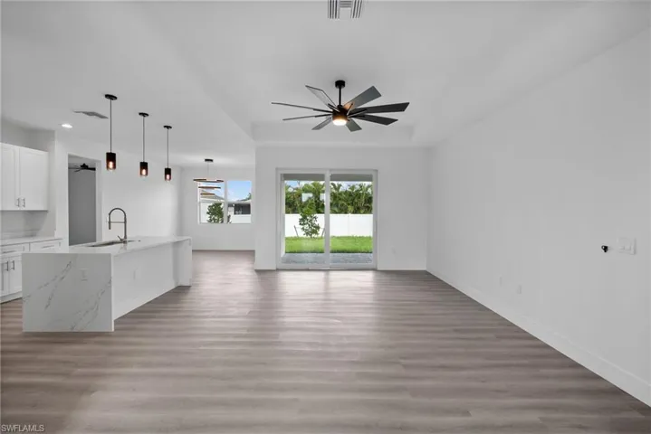 Unfurnished living room with ceiling fan, light wood-type flooring, and sink