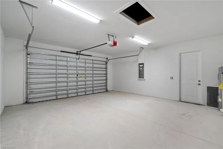 Garage featuring a garage door opener, electric water heater, and electric panel