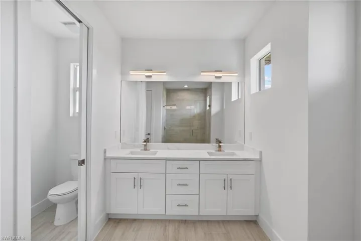 Bathroom with wood-type flooring, vanity, a shower with shower door, and toilet