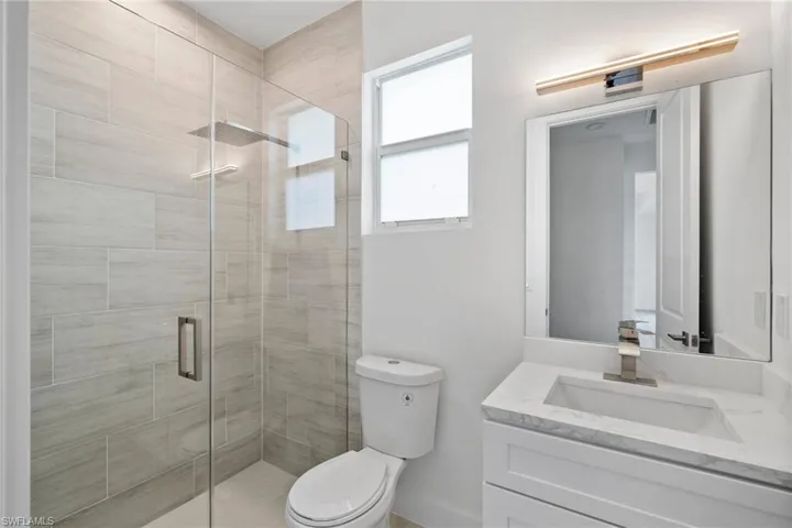 Bathroom featuring an enclosed shower, vanity, and toilet