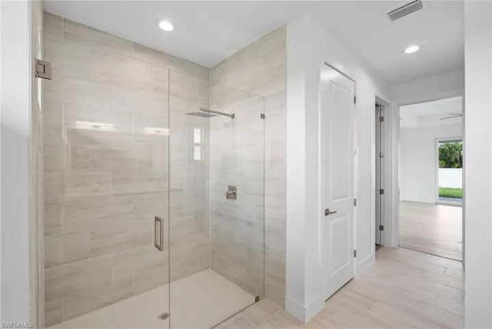 Bathroom featuring ceiling fan and a shower with door