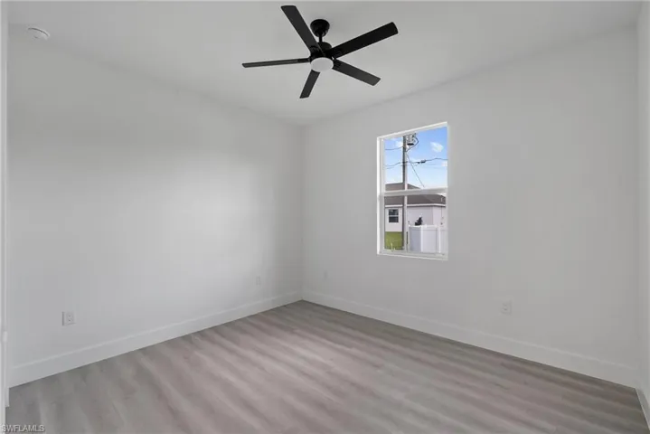 Empty room with ceiling fan and light hardwood / wood-style flooring