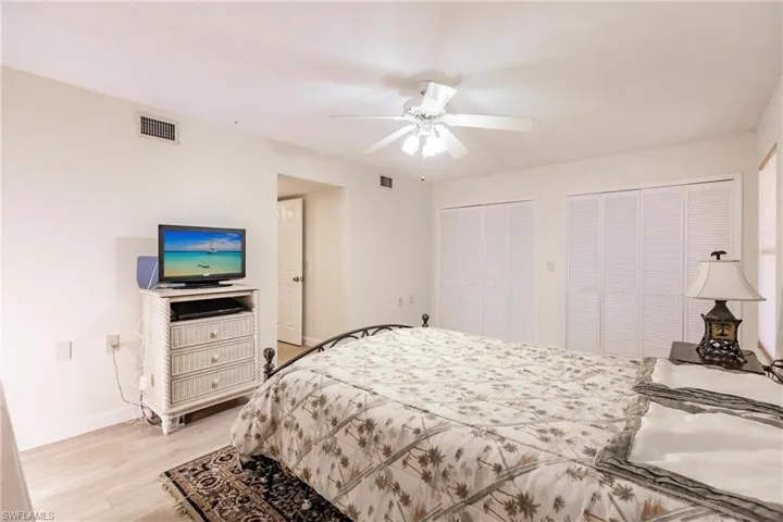 Bedroom with ceiling fan, light hardwood / wood-style floors, and two closets