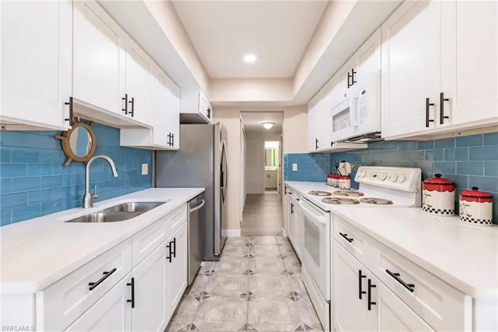 Kitchen featuring white cabinets, white appliances, sink, and light tile patterned floors