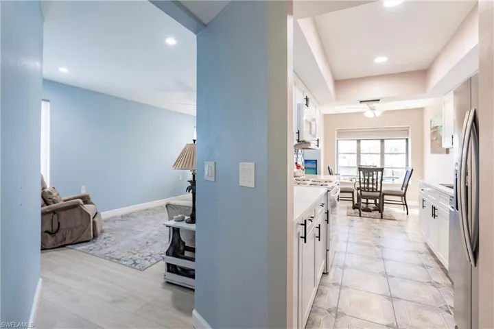 Kitchen with white electric stove, white cabinetry, and a tray ceiling
