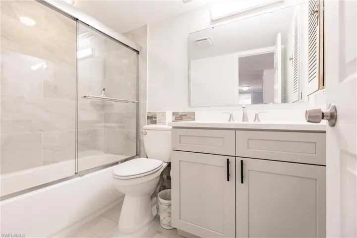 Full bathroom featuring vanity, toilet, and enclosed tub / shower combo